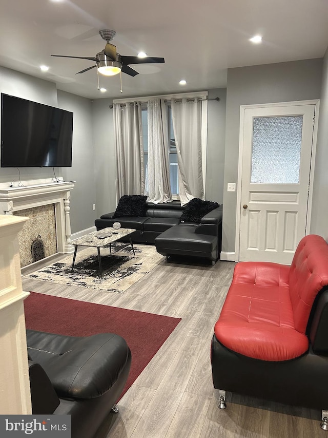 living room featuring wood-type flooring, ceiling fan, and a fireplace