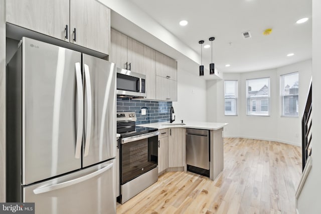 kitchen with decorative light fixtures, tasteful backsplash, sink, kitchen peninsula, and stainless steel appliances