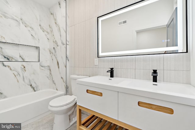 full bathroom featuring tile walls, vanity, tiled shower / bath, and toilet