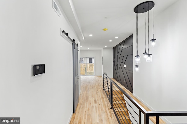 hallway with a barn door and light hardwood / wood-style floors