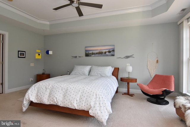 carpeted bedroom with crown molding, a tray ceiling, and ceiling fan