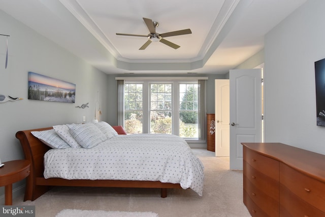 carpeted bedroom featuring a tray ceiling, ornamental molding, and ceiling fan