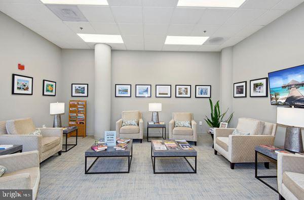 living room featuring a paneled ceiling and light colored carpet