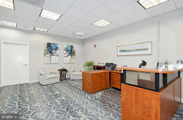 office area featuring dark colored carpet and a drop ceiling