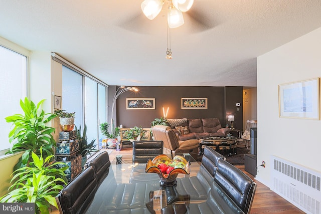 living room featuring ceiling fan, a textured ceiling, radiator heating unit, and wood-type flooring