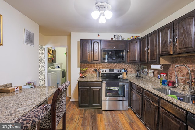 kitchen featuring stainless steel appliances, light stone countertops, sink, and washing machine and clothes dryer