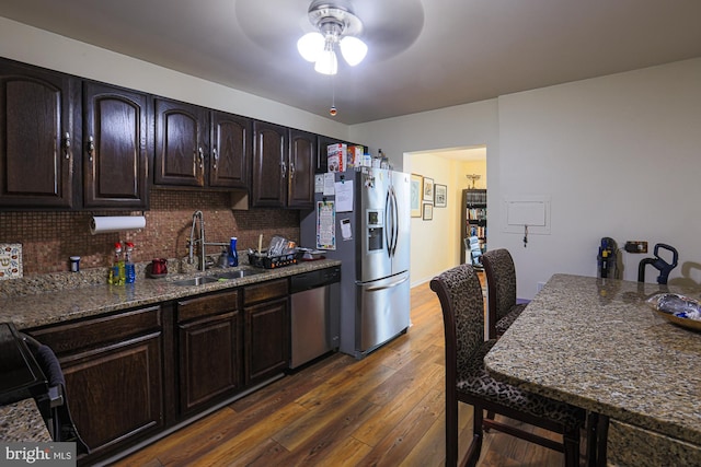 kitchen with sink, dark brown cabinets, stainless steel appliances, and stone countertops