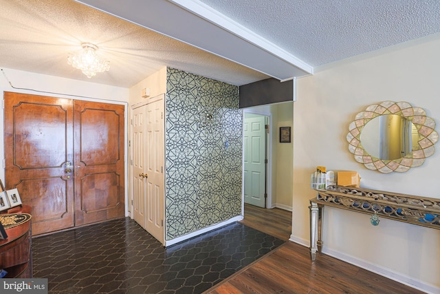 foyer entrance with dark hardwood / wood-style flooring, a textured ceiling, and a notable chandelier