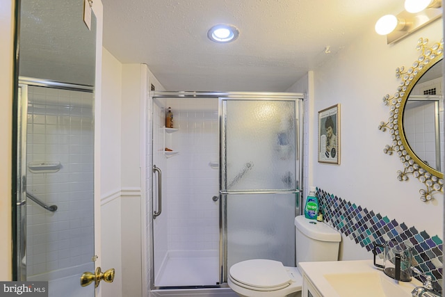 bathroom with vanity, a textured ceiling, a shower with door, and toilet