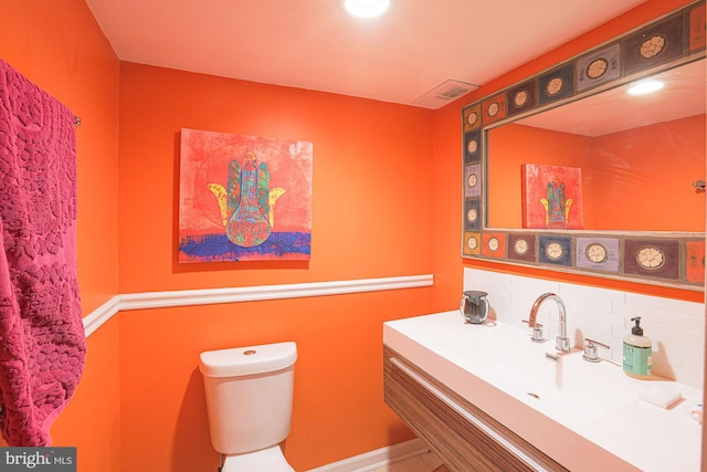 bathroom featuring vanity, backsplash, and toilet