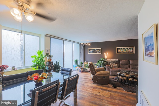 living room with ceiling fan, dark hardwood / wood-style floors, floor to ceiling windows, and a textured ceiling