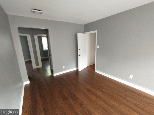 unfurnished room with dark wood-type flooring