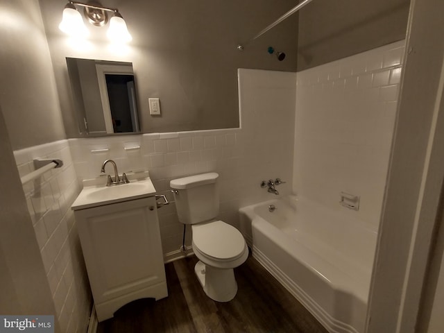 full bathroom with toilet,  shower combination, tile walls, vanity, and hardwood / wood-style floors