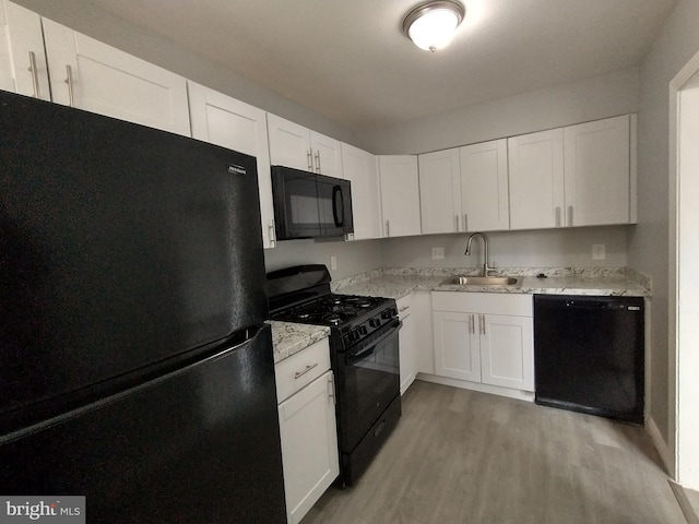 kitchen with white cabinetry, sink, black appliances, and light wood-type flooring