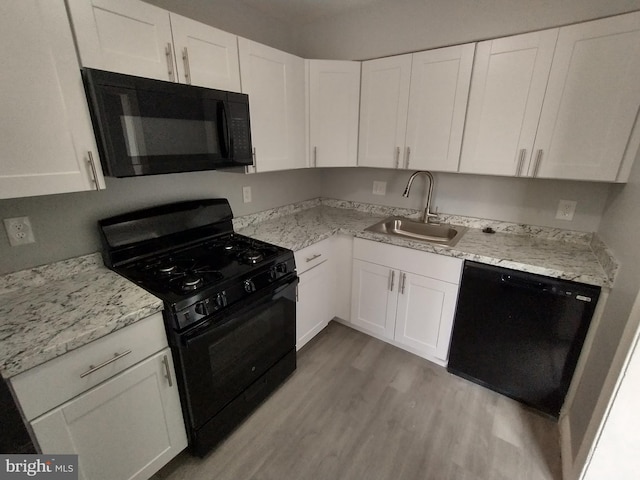 kitchen with white cabinetry, sink, light hardwood / wood-style floors, black appliances, and light stone countertops