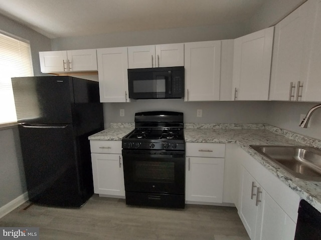 kitchen with white cabinetry, sink, light stone counters, black appliances, and light hardwood / wood-style flooring