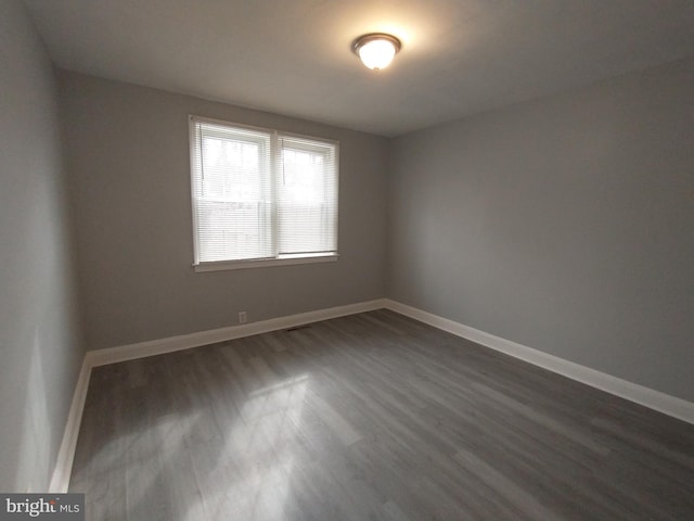 unfurnished room with dark wood-type flooring