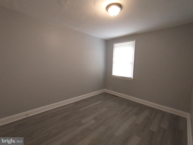 unfurnished room with dark wood-type flooring