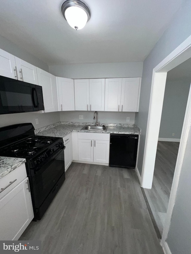 kitchen featuring sink, hardwood / wood-style floors, light stone counters, black appliances, and white cabinets