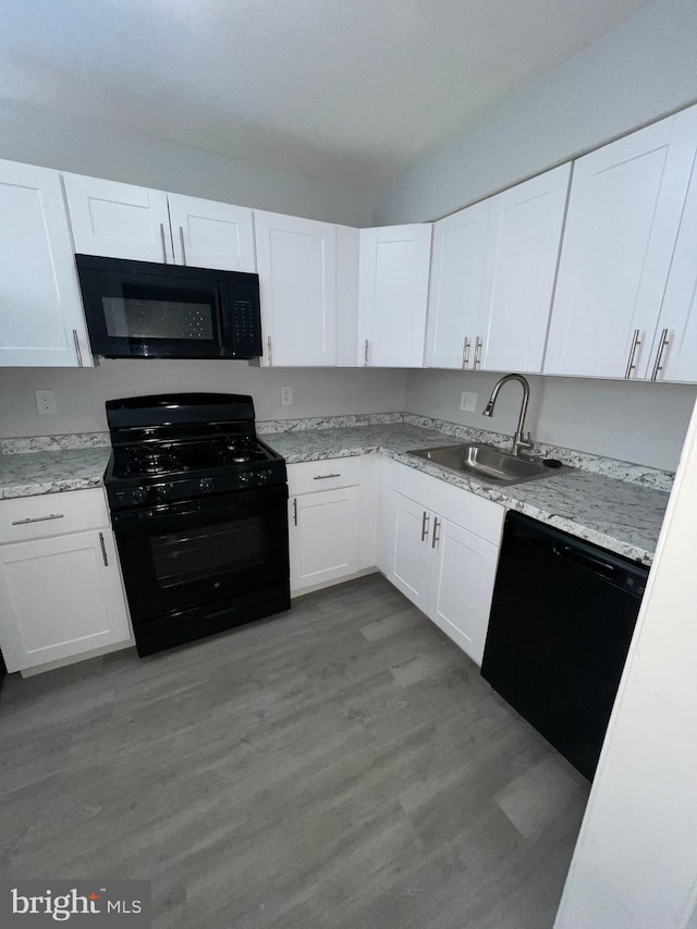 kitchen with white cabinetry, wood-type flooring, sink, light stone counters, and black appliances