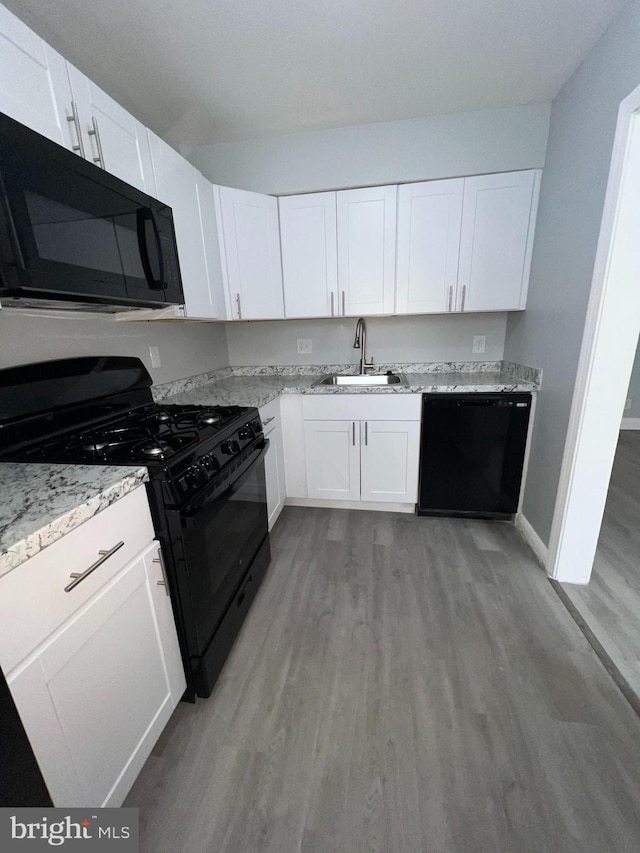 kitchen with white cabinets, sink, light hardwood / wood-style flooring, and black appliances