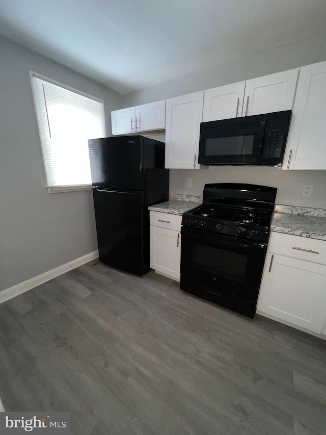 kitchen featuring light stone countertops, white cabinets, light hardwood / wood-style floors, and black appliances