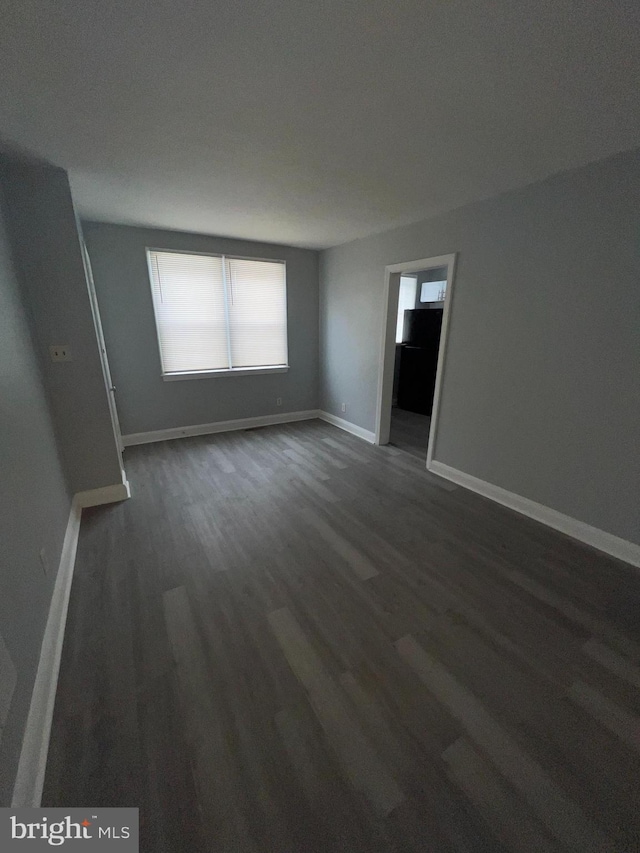 unfurnished room with dark wood-type flooring