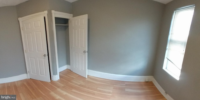 unfurnished bedroom featuring a closet, multiple windows, and light hardwood / wood-style flooring