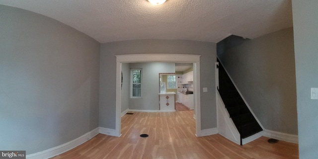 hallway with light hardwood / wood-style floors and a textured ceiling