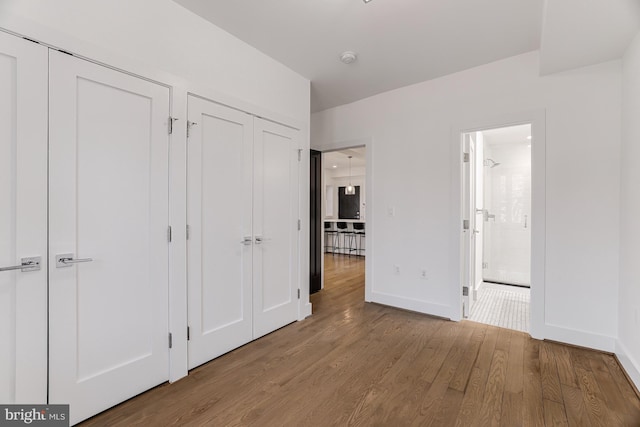 unfurnished bedroom featuring light hardwood / wood-style floors, multiple closets, and ensuite bathroom