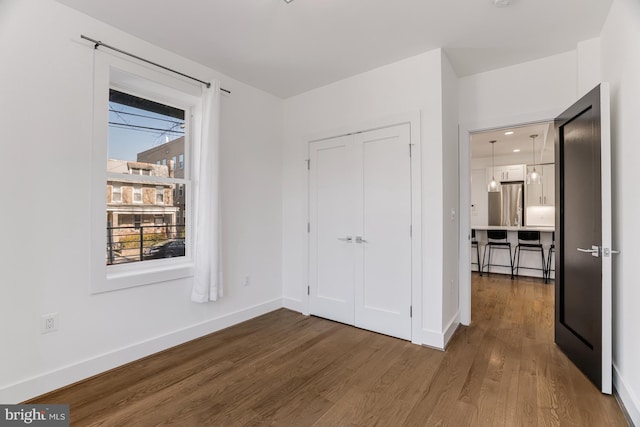 unfurnished bedroom with dark wood-type flooring and stainless steel fridge