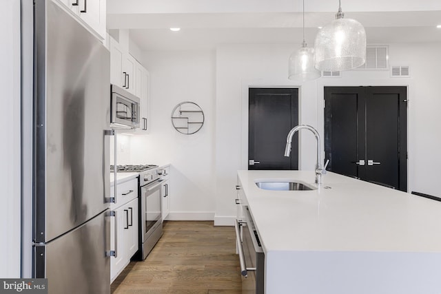 kitchen featuring white cabinetry, stainless steel appliances, sink, and a kitchen island with sink