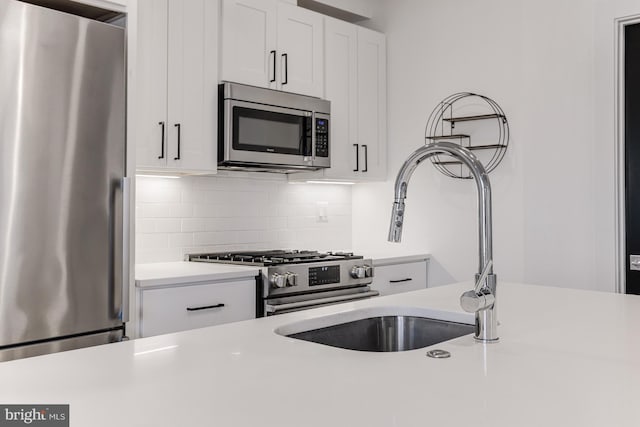 kitchen featuring stainless steel appliances, white cabinetry, sink, and backsplash