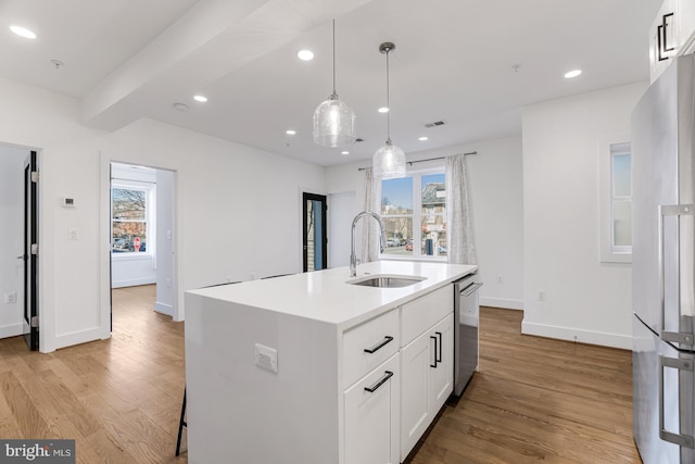 kitchen with sink, a center island with sink, stainless steel dishwasher, pendant lighting, and white cabinets