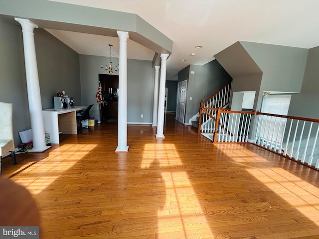 bonus room with ornate columns, a notable chandelier, and light hardwood / wood-style floors