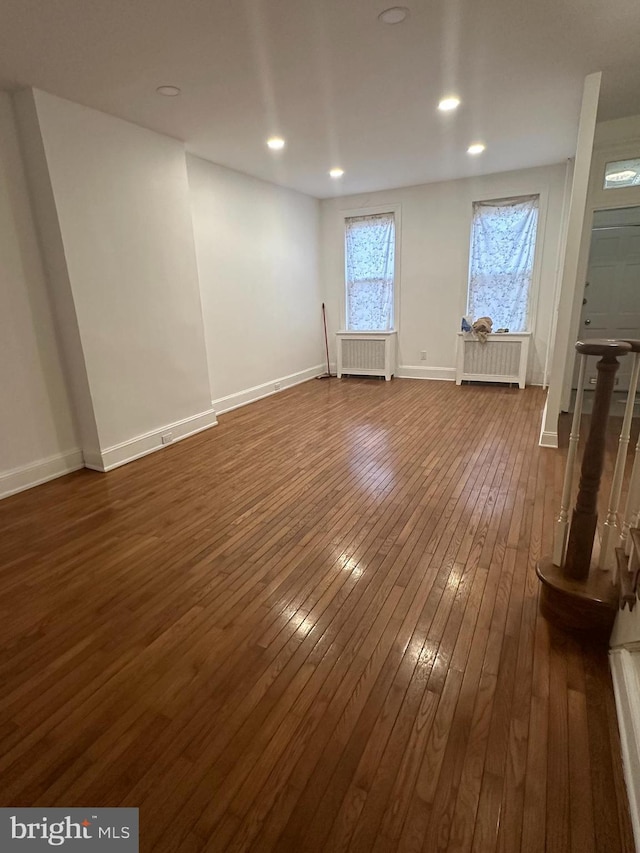 unfurnished room with dark wood-style floors, radiator heating unit, recessed lighting, and baseboards