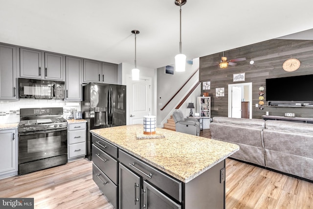 kitchen with gray cabinets, a kitchen island, wooden walls, hanging light fixtures, and black appliances