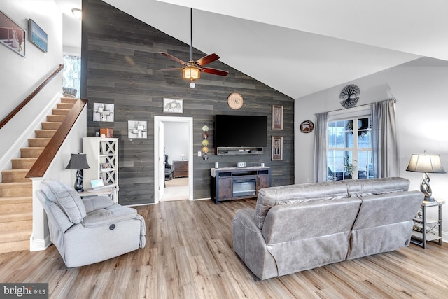 living room with high vaulted ceiling, ceiling fan, and light hardwood / wood-style flooring