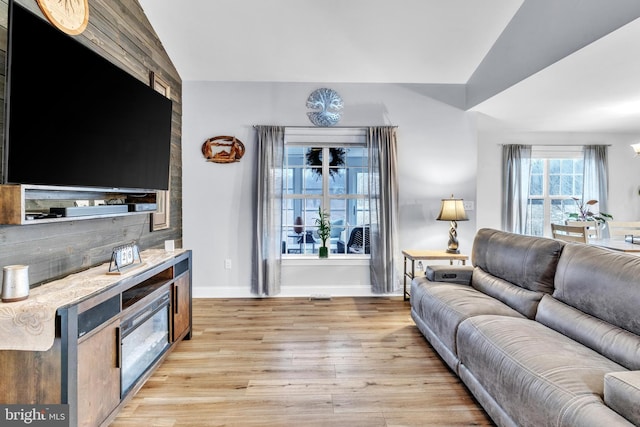 living room featuring lofted ceiling and light hardwood / wood-style floors