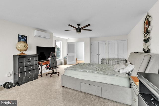 carpeted bedroom with ceiling fan, two closets, and a wall unit AC