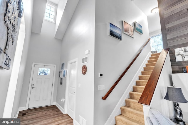 foyer with plenty of natural light, a towering ceiling, and light hardwood / wood-style floors