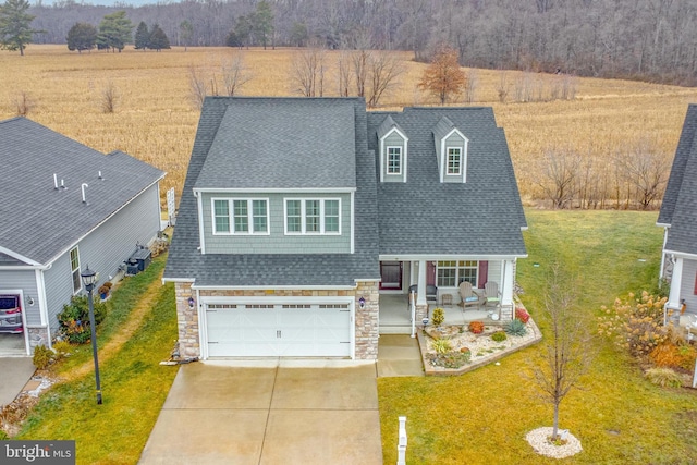 view of front facade featuring a garage, a rural view, covered porch, and a front lawn