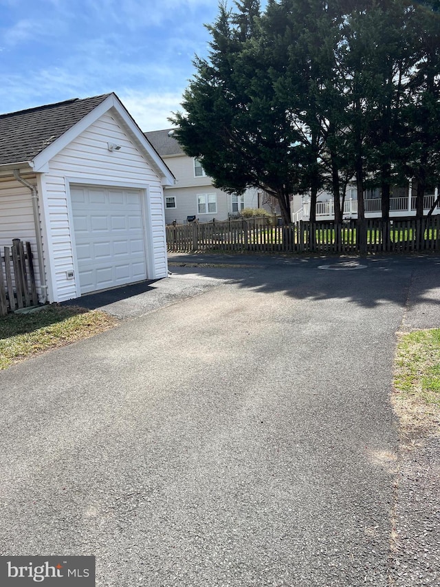 garage featuring fence and asphalt driveway