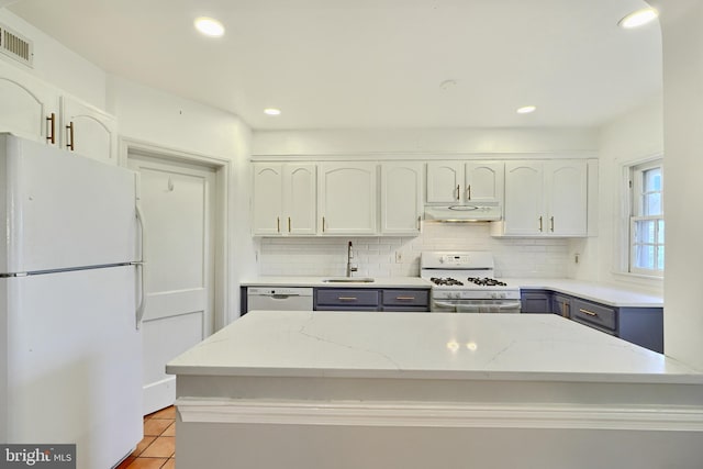 kitchen featuring sink, white cabinetry, white appliances, light stone countertops, and backsplash