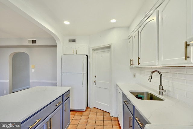 kitchen with sink, white appliances, white cabinetry, backsplash, and light stone counters