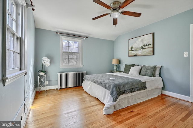 bedroom with ceiling fan, lofted ceiling, radiator heating unit, and light hardwood / wood-style floors