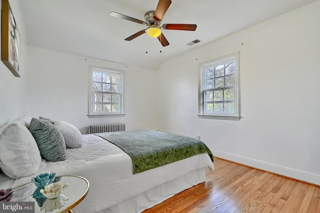 bedroom featuring ceiling fan, radiator heating unit, and wood-type flooring