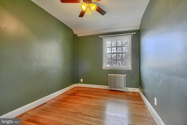 empty room featuring light hardwood / wood-style flooring, radiator heating unit, lofted ceiling, and ceiling fan