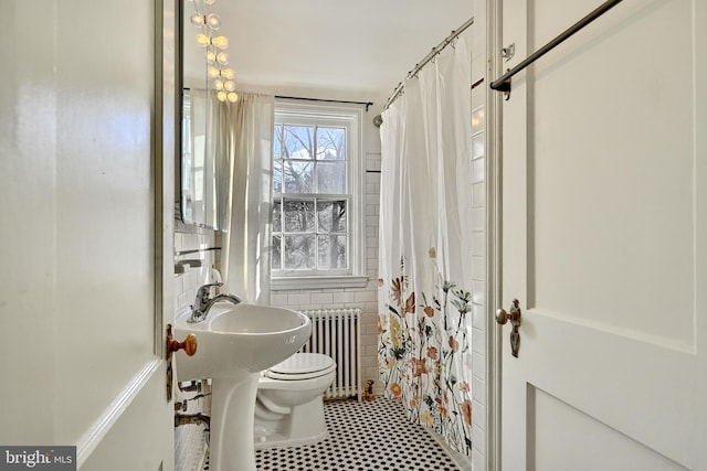 bathroom with walk in shower, radiator heating unit, tile walls, and toilet