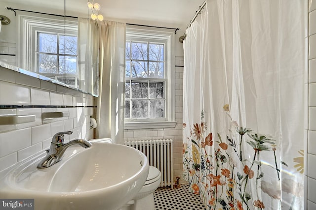 bathroom with radiator heating unit, sink, and tile walls